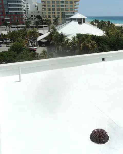 White rooftop coating and waterproofing surface on a coastal building overlooking the water.