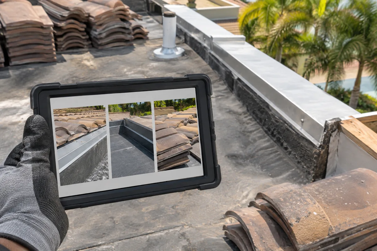 AI-generated example of a gloved hand holding a tablet with roof-detail photographs at a roofing work area.