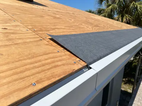 Nailed plywood roof deck with underlayment and a white metal drip edge