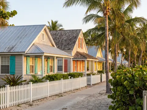 Delray Beach cottages with metal and shingle roofs behind a picket fence