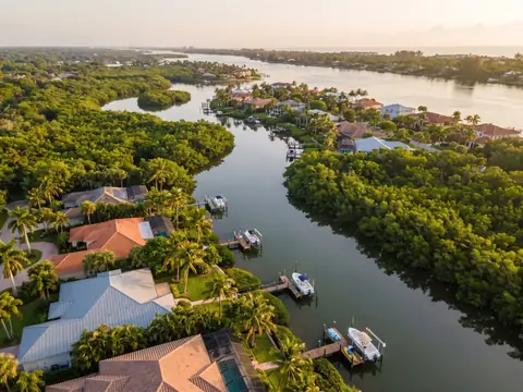 Aerial view of waterfront homes with tile and metal roofs on a Jupiter river