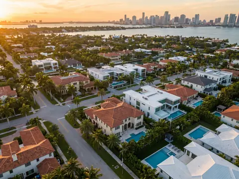 Aerial view of tile and flat roofs in a Miami neighborhood, the bay and skyline beyond