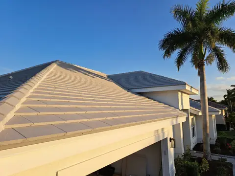 New light gray concrete tile roof on a white stucco home under a royal palm