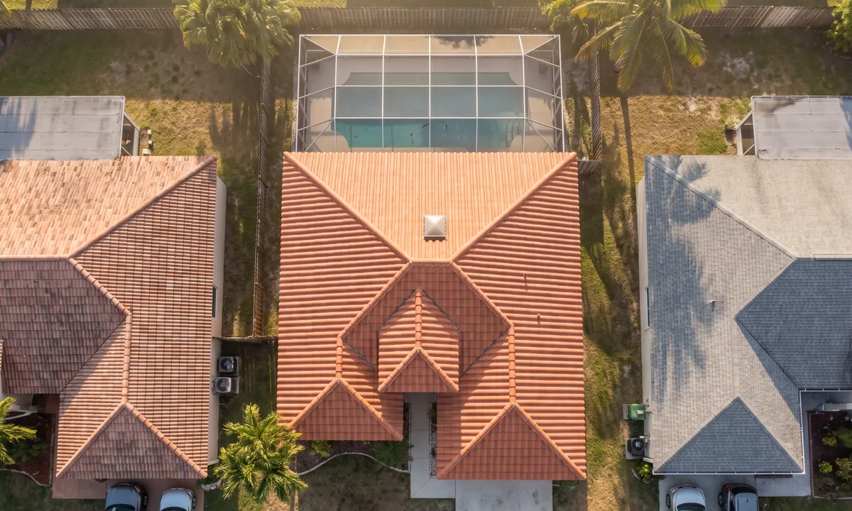 A newly finished terracotta barrel tile roof with hips, ridges and a valley among neighbouring homes.