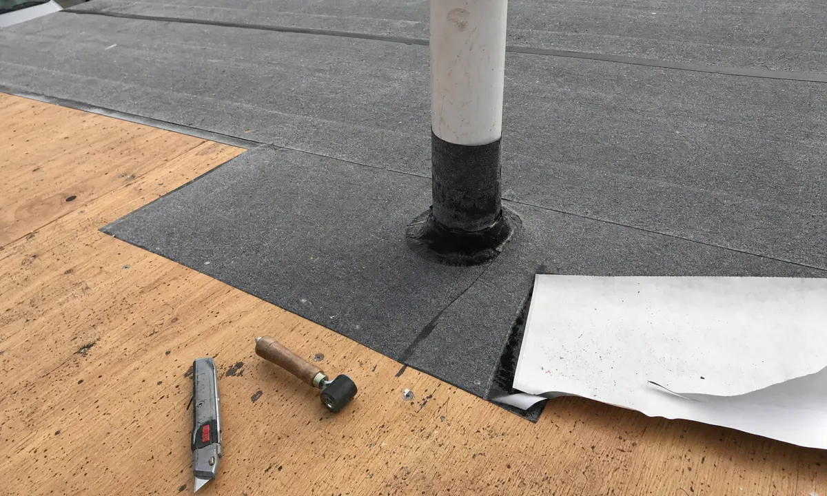 Self-adhered secondary water barrier membrane lapped over plywood and sealed around a plumbing vent.