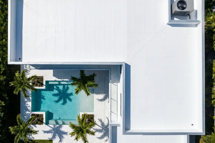 Aerial view of a modern white home with a new single-ply flat roof.