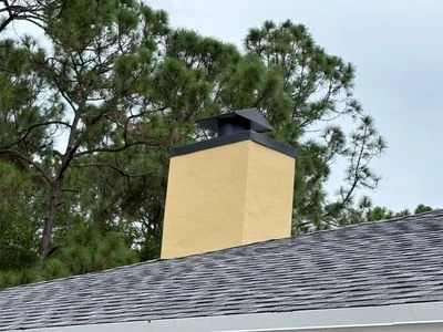 Architectural shingles below a finished chimney in a reviewed Perkins project photograph.